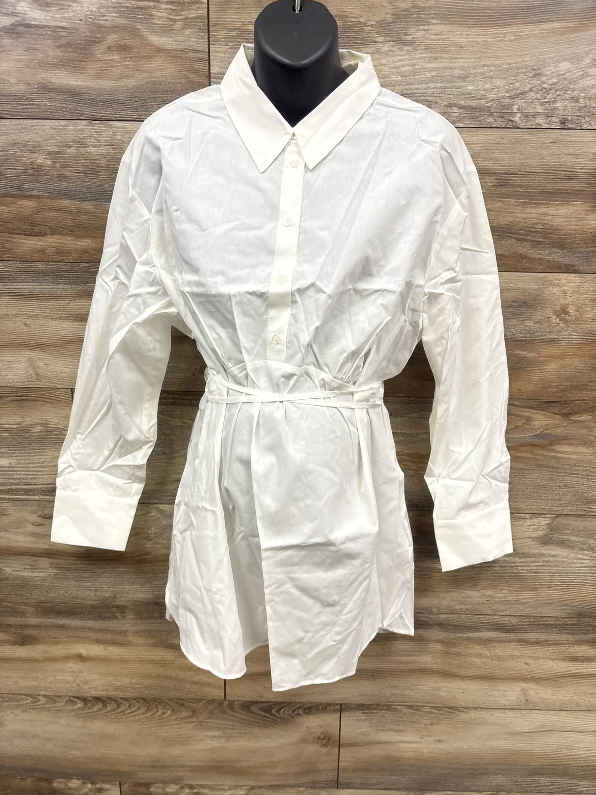 White long sleeve button-down shirt dress with waist tie on mannequin, wooden background