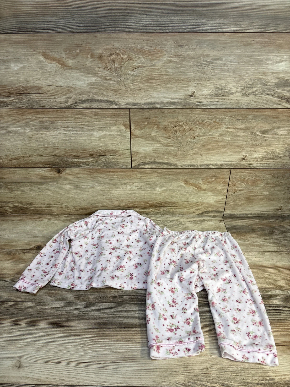 Flat lay of Girls Laura Ashley pink floral 2-piece pajama set size 2T showing long-sleeve top and elastic-waist pants on wood floor