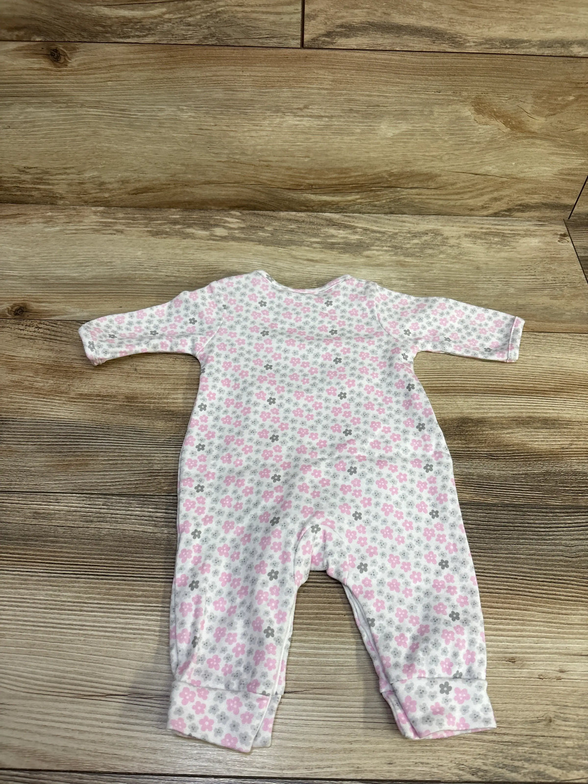 Flat lay of white preemie baby sleeper with pink and gray floral print on a wood background