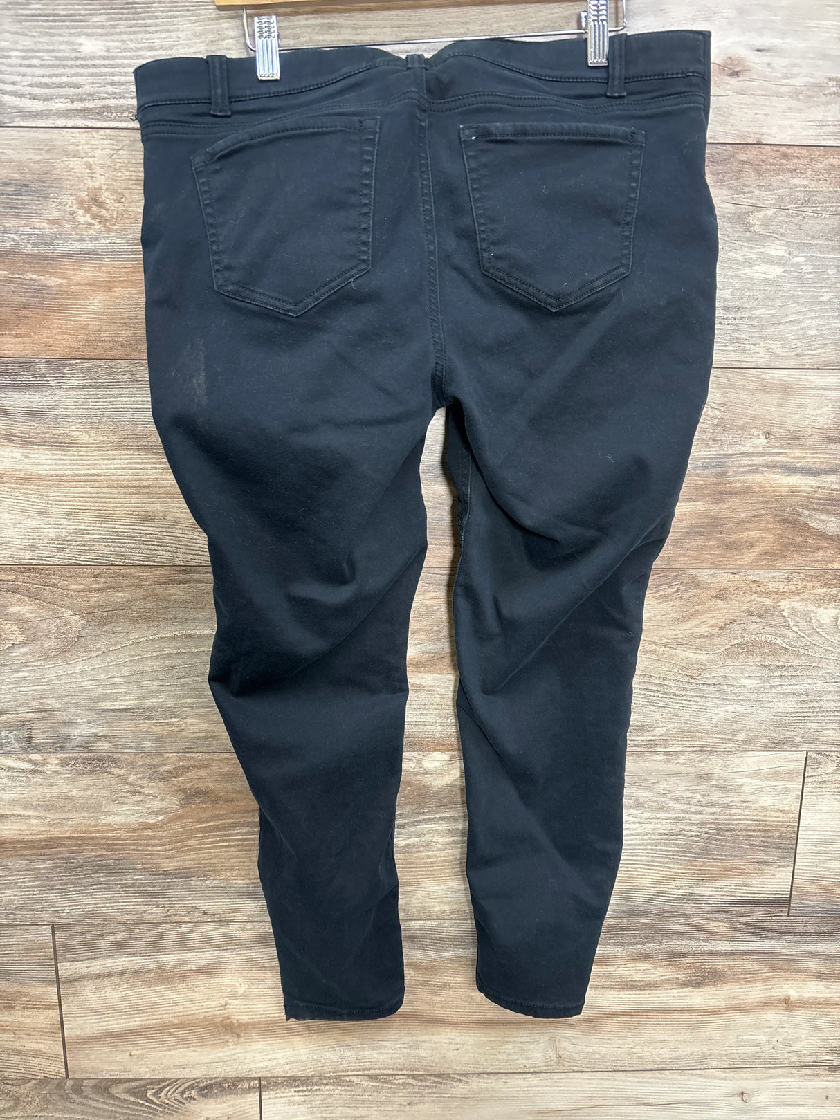 Black kids' jeans with back pockets displayed on wooden floor, gently used condition
