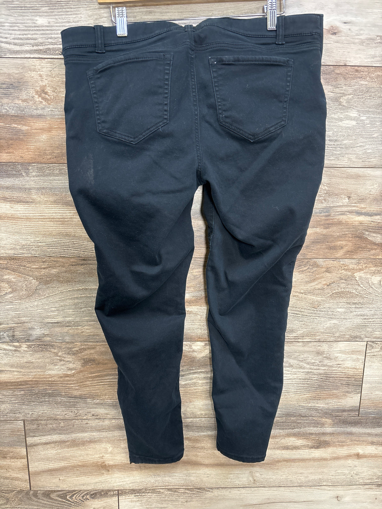 Black kids' jeans with back pockets displayed on wooden floor, gently used condition