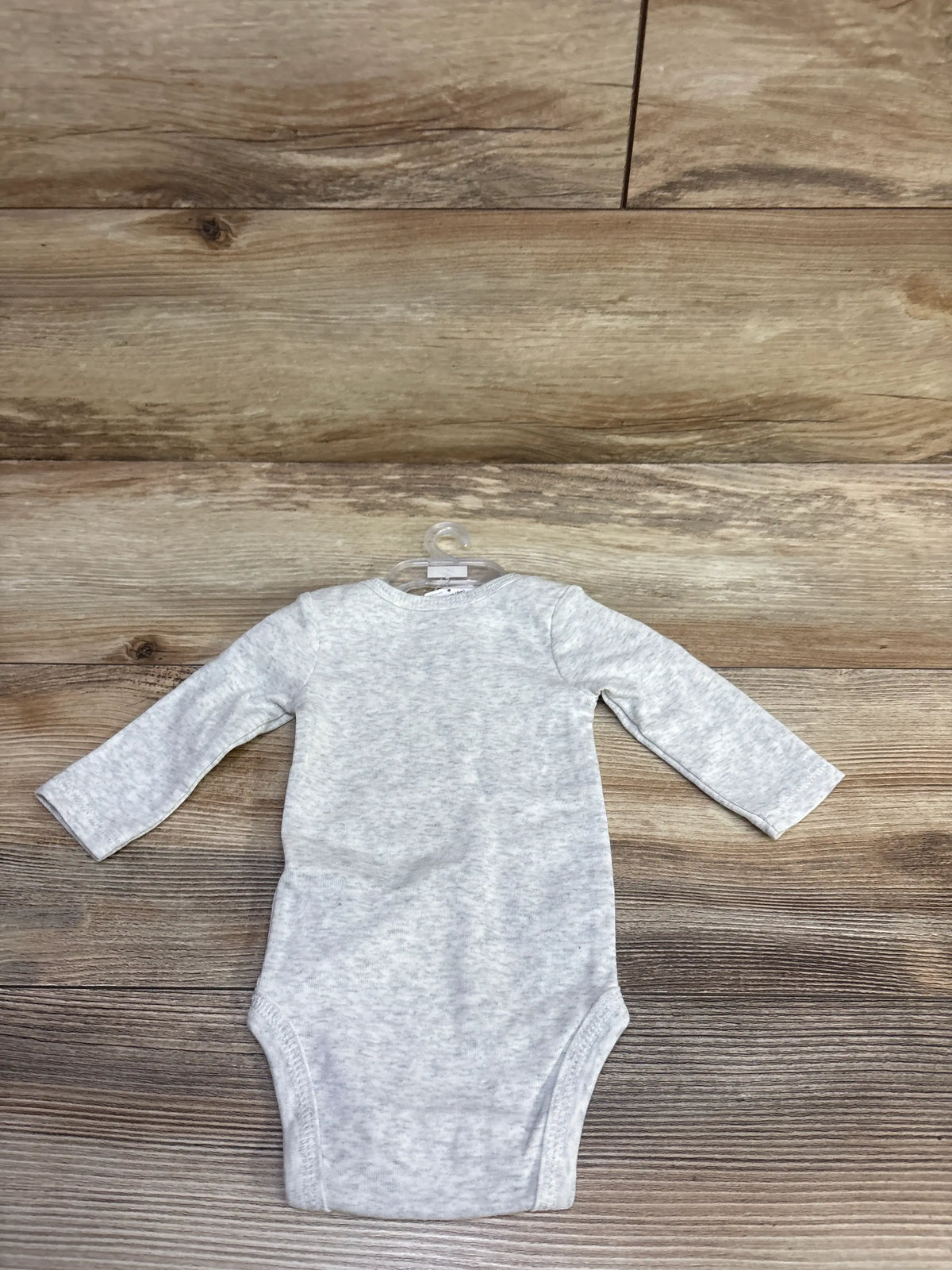 Front view of grey long-sleeve newborn Thanksgiving baby bodysuit on a hanger against a wooden background