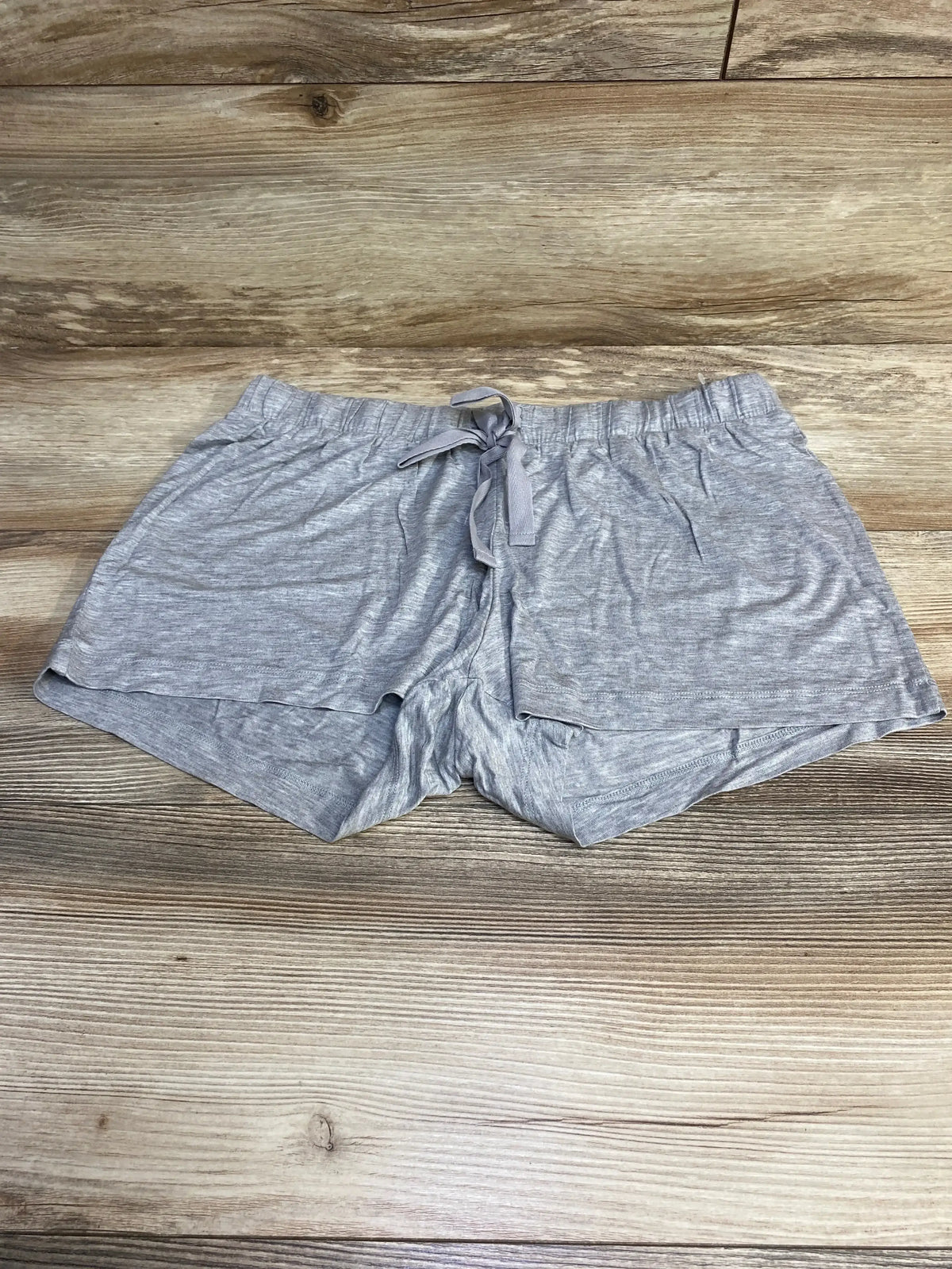Flat lay of grey Gap Body maternity modal shorts showing elastic drawstring waistband and layered hem on wood background