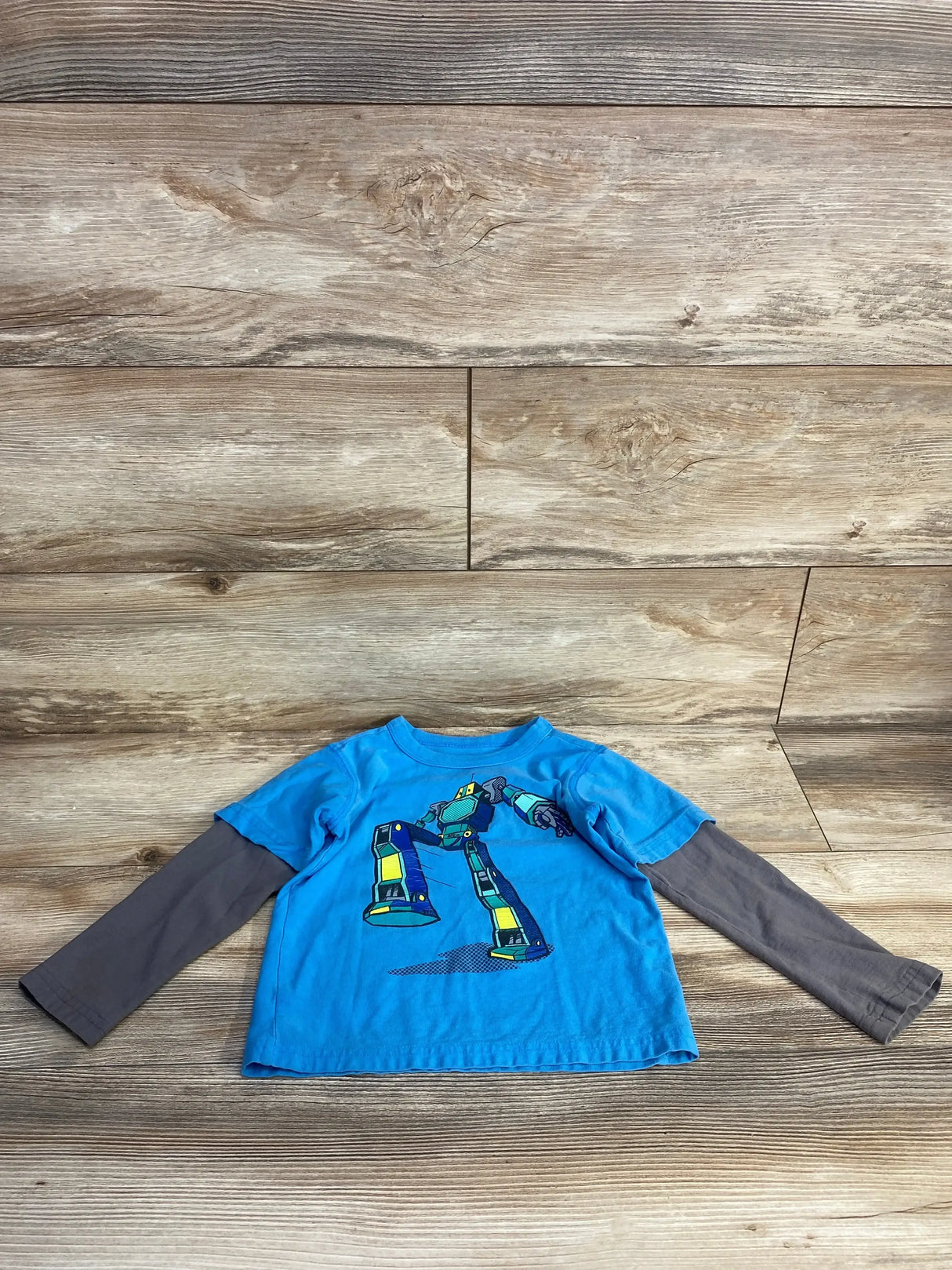 Front flat lay of blue layered toddler tee with gray long sleeves and robot graphic, size 4T on wood background