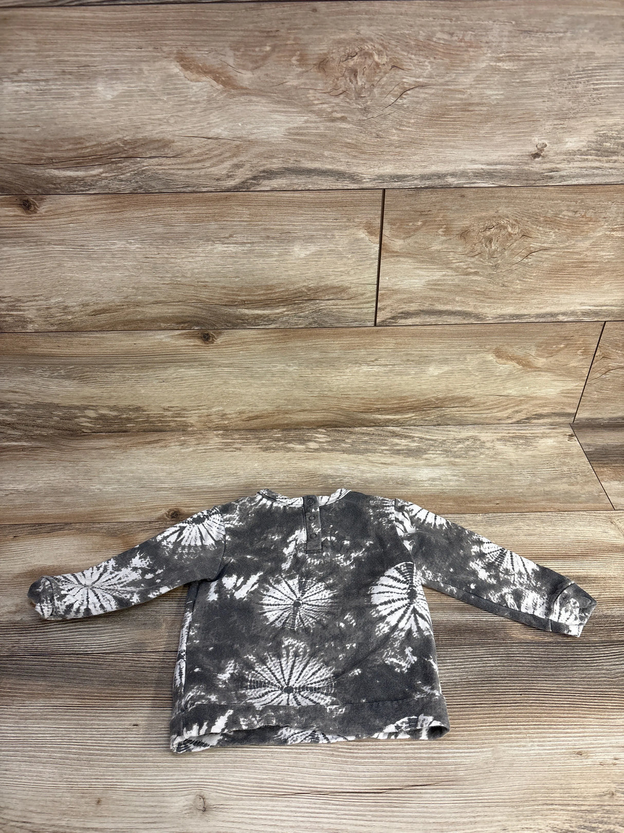 Back view of gray and white tie-dye long sleeve baby shirt on wooden background