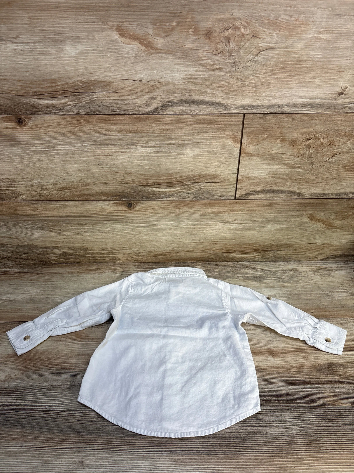 White long sleeve toddler shirt with button cuffs on wood background