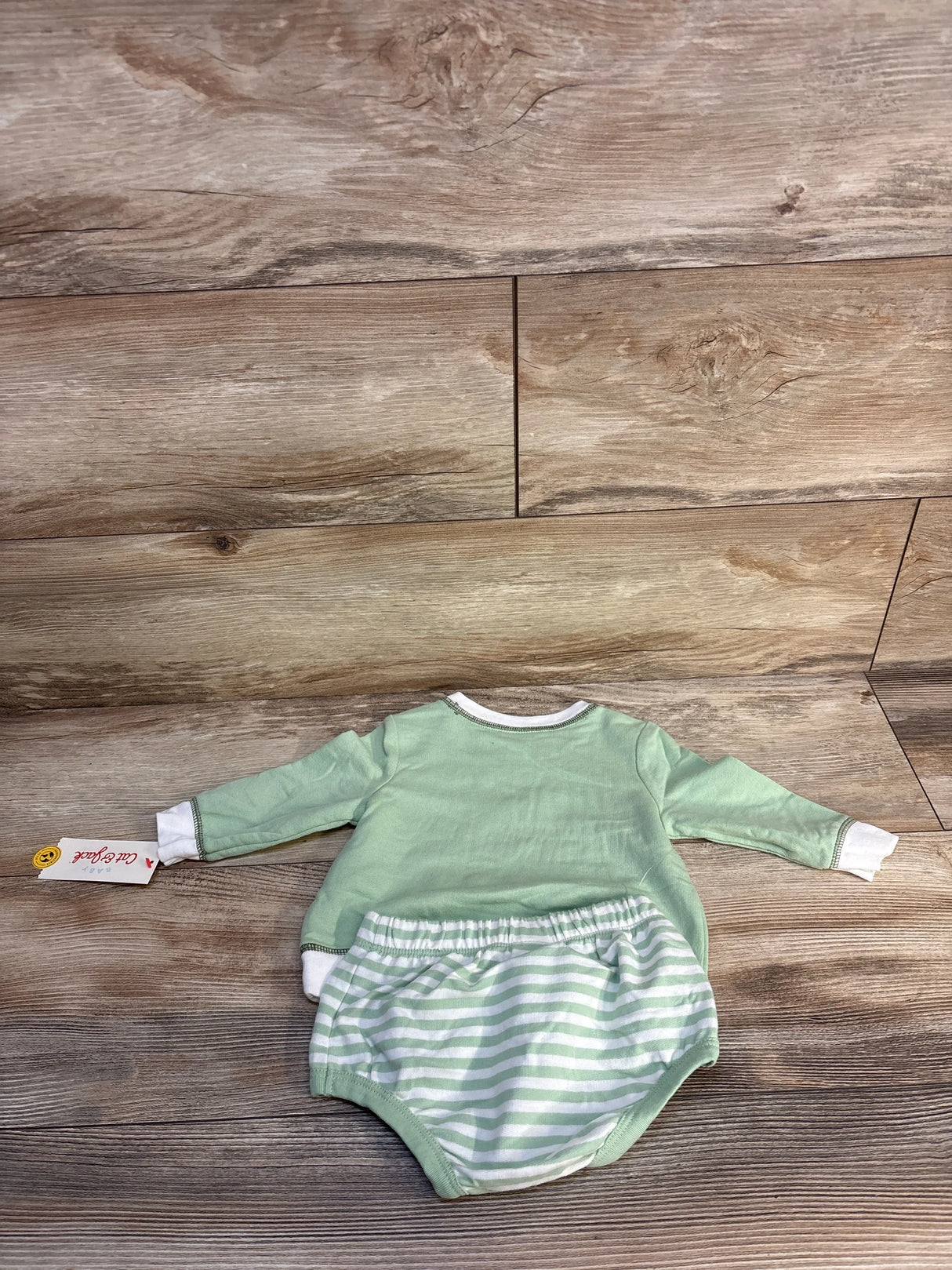Mint green baby long sleeve romper with striped shorts on wooden background