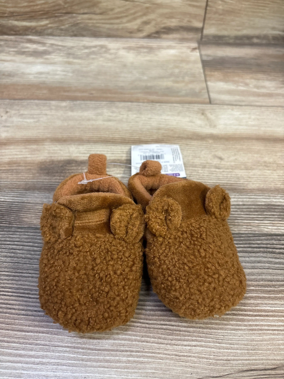 Top view of brown Gerber fleece slipper booties showcasing textured fabric and animal ear details on a wood grain background