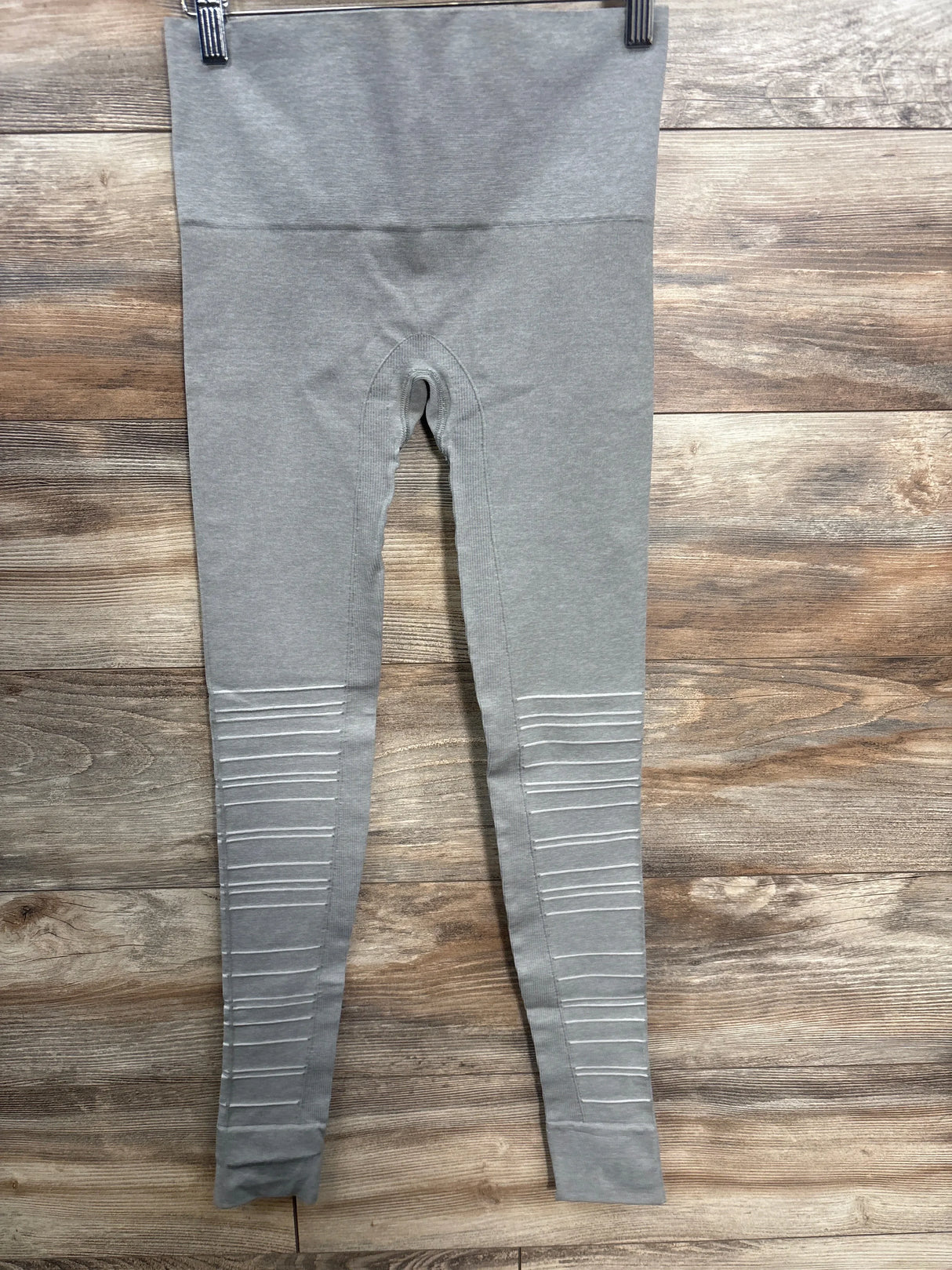 Gray maternity leggings with ribbed detailing on legs, displayed against wooden background