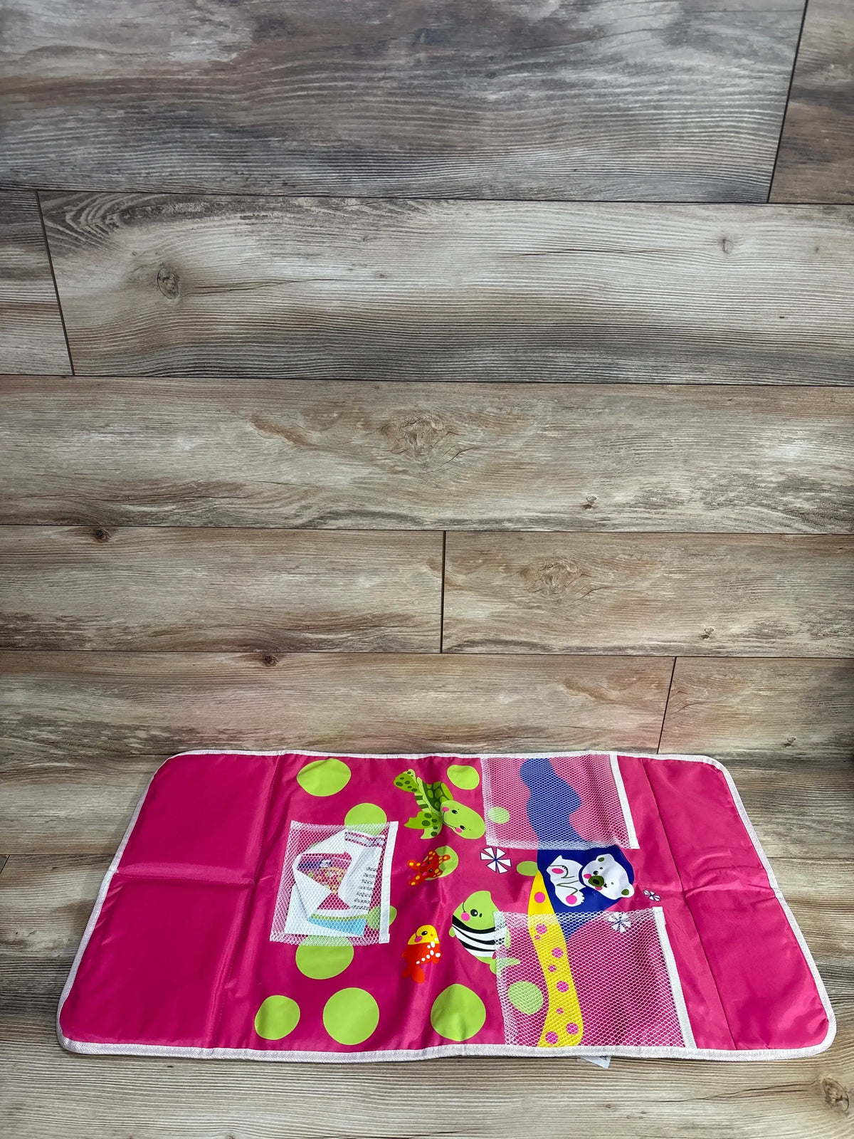 Top-down view of bath kneeling pad with organizer showcasing two mesh pockets and colorful animal and polka-dot print on wood floor