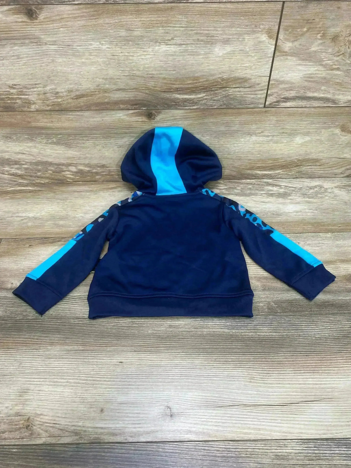 Back view of navy Athletic Works toddler full-zip hoodie with hood and bright blue sleeve and center stripe on wood floor