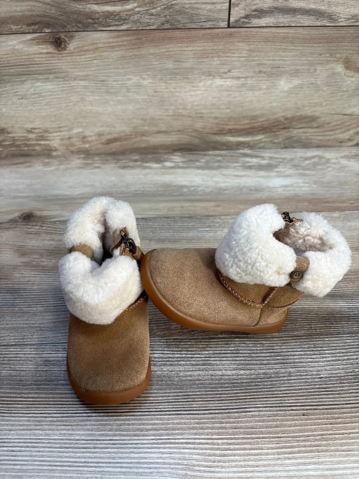 Pair of toddler brown suede boots with faux fur lining on wood floor