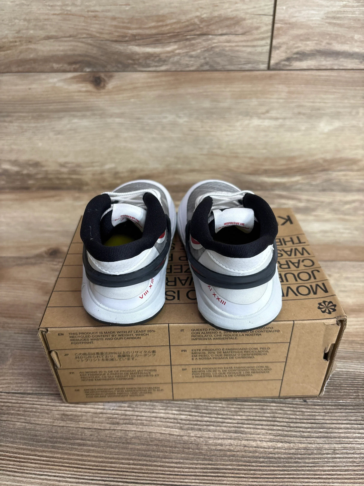 Rear view of Nike Kyrie 8 TD toddler sneakers showcasing black padded collars and red heel accents on a Move to Zero box over wood flooring