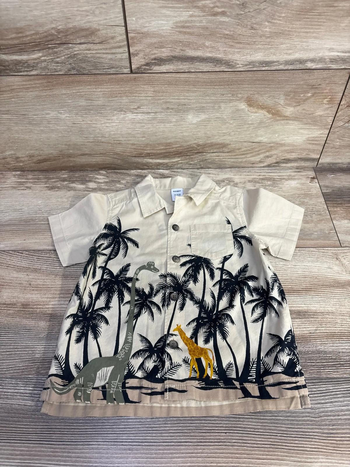 Front view of Old Navy beige button up shirt for 12 to 18 months with short sleeves, collar, breast pocket, dinosaur print
