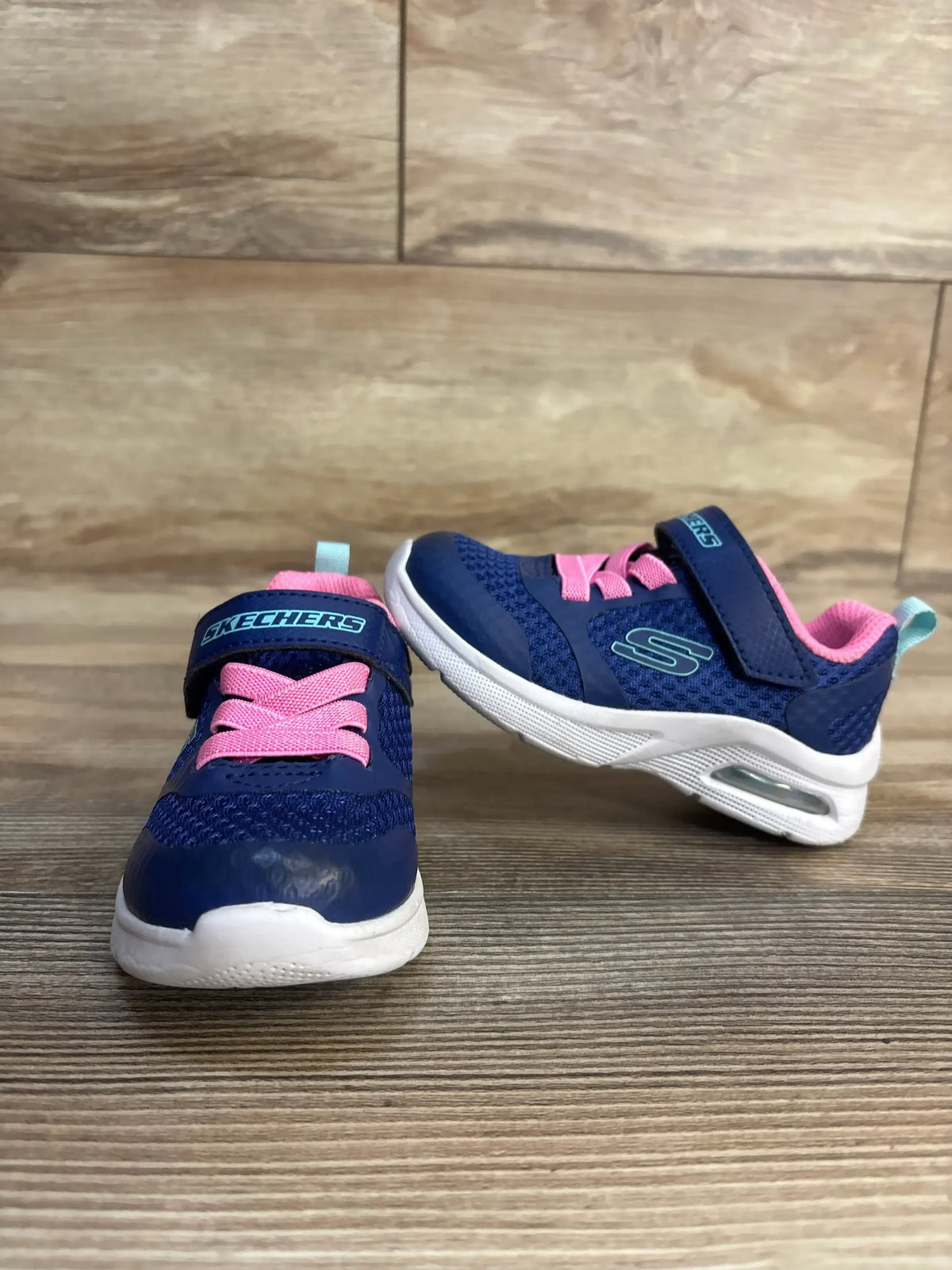 Blue and pink Skechers toddler sneakers with velcro straps and air cushion soles on wood floor