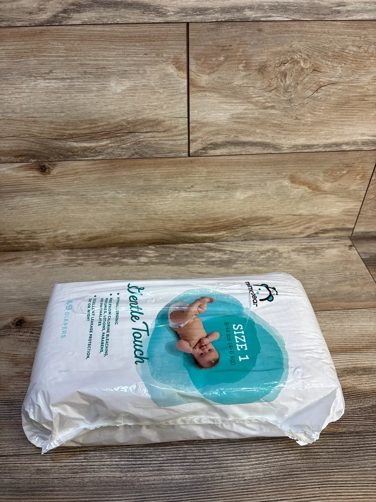 Pack of size 1 Gentle Touch disposable baby diapers on wood floor