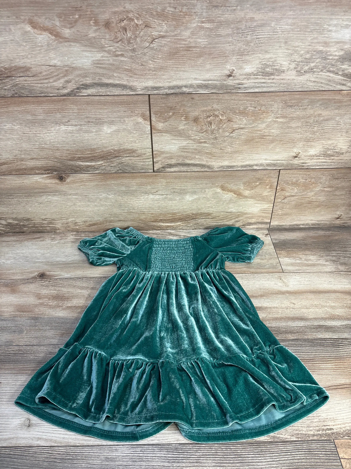 Front view of Carter’s 4T green velvet dress showcasing puff sleeves, smocked bodice, and ruffled hem on wood flooring