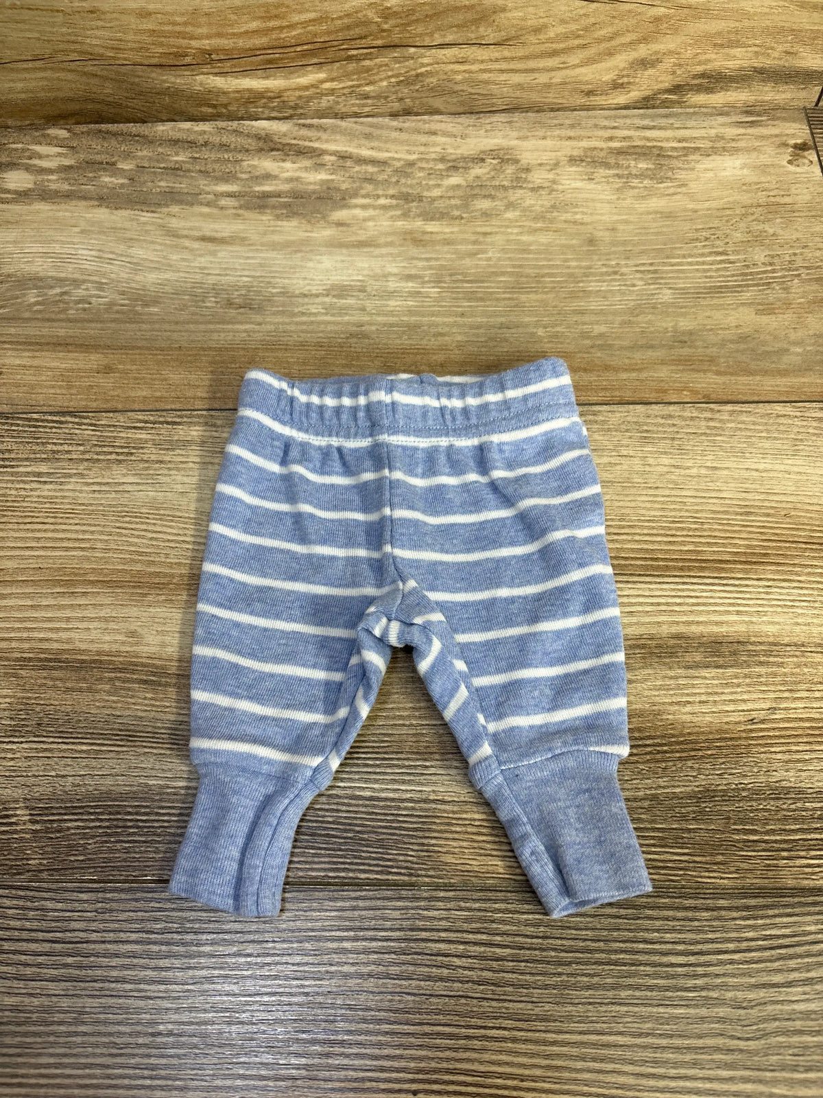 Front view of Child of Mine preemie pants showcasing blue and white stripes, elastic waistband, and ribbed cuffs on wood