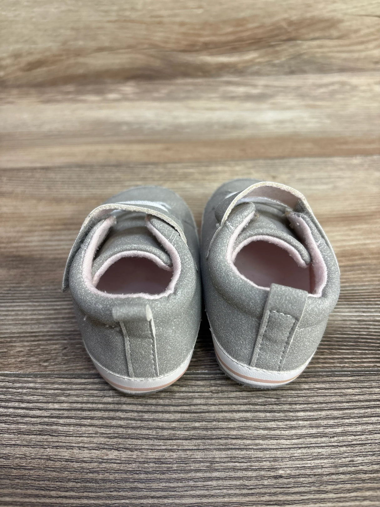 Pair of gray toddler sneakers with velcro straps on wooden floor, children's resale shoe