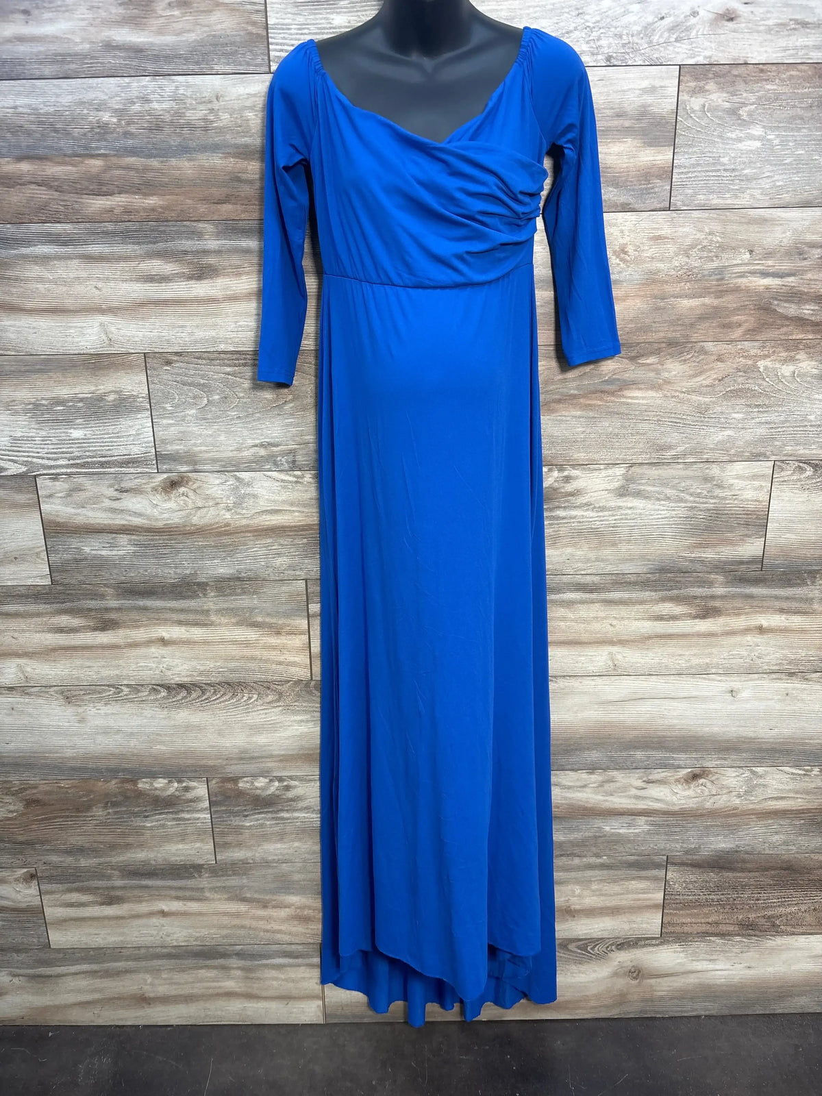 Royal blue long sleeve maxi dress with draped neckline on mannequin against wood panel wall