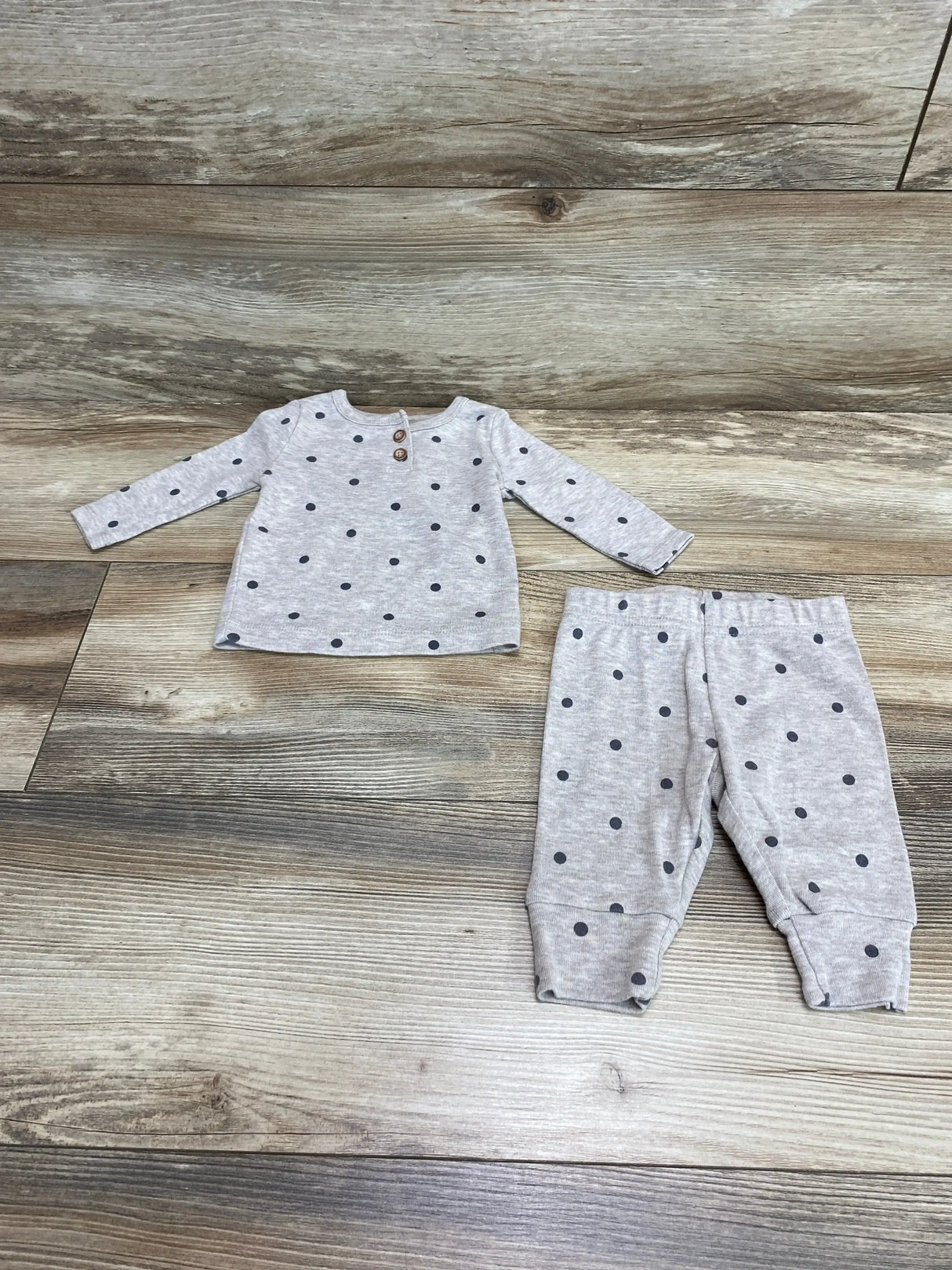 Flat lay of Just One You 2-piece gray polka dot long-sleeve top and cuffed pants, size 3 months, showing wooden buttons and elastic waist on wood floor
