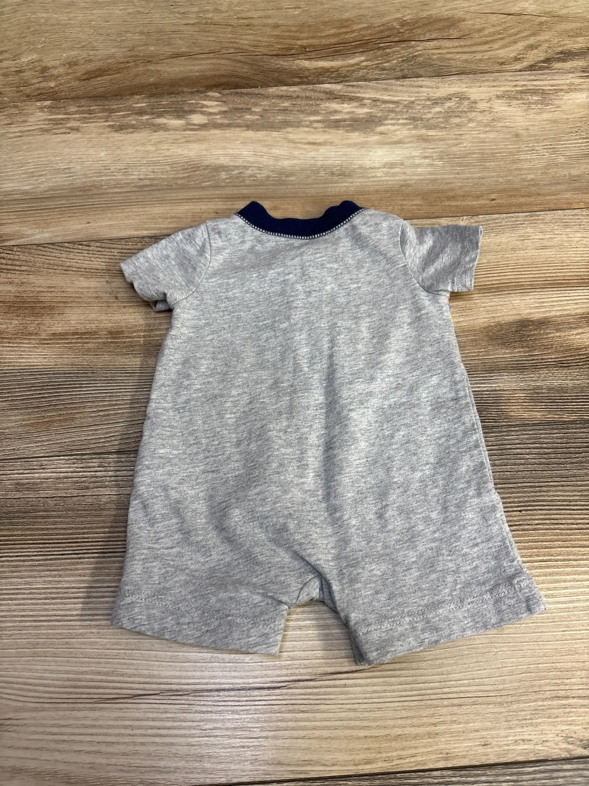 Gray baby romper with short sleeves and navy collar on wooden background