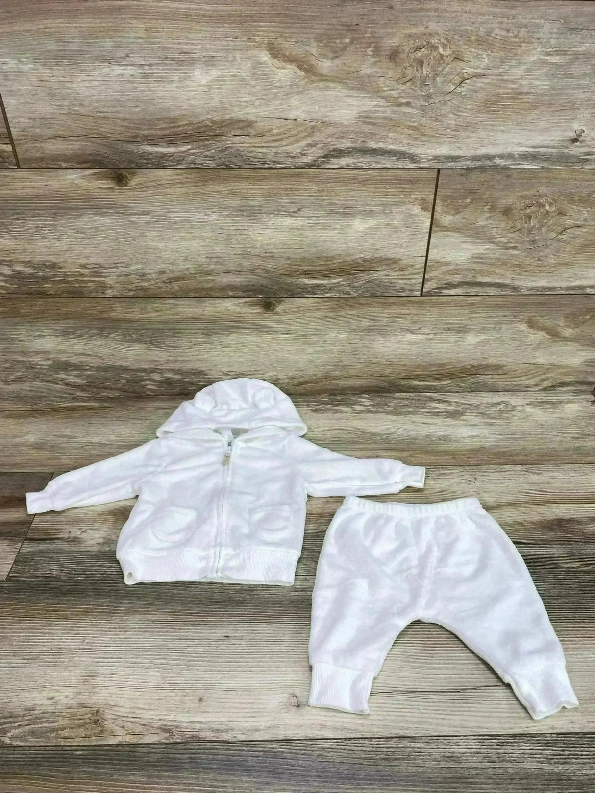 Flat lay of white Carter’s terry cloth hoodie and pants, size 3M, hooded zip top with pockets and elastic waist on wood