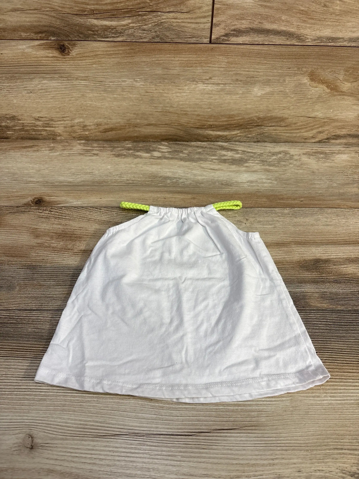 Top-down view of white Okie Dokie braided strap toddler top showcasing neon yellow braided straps with wood background