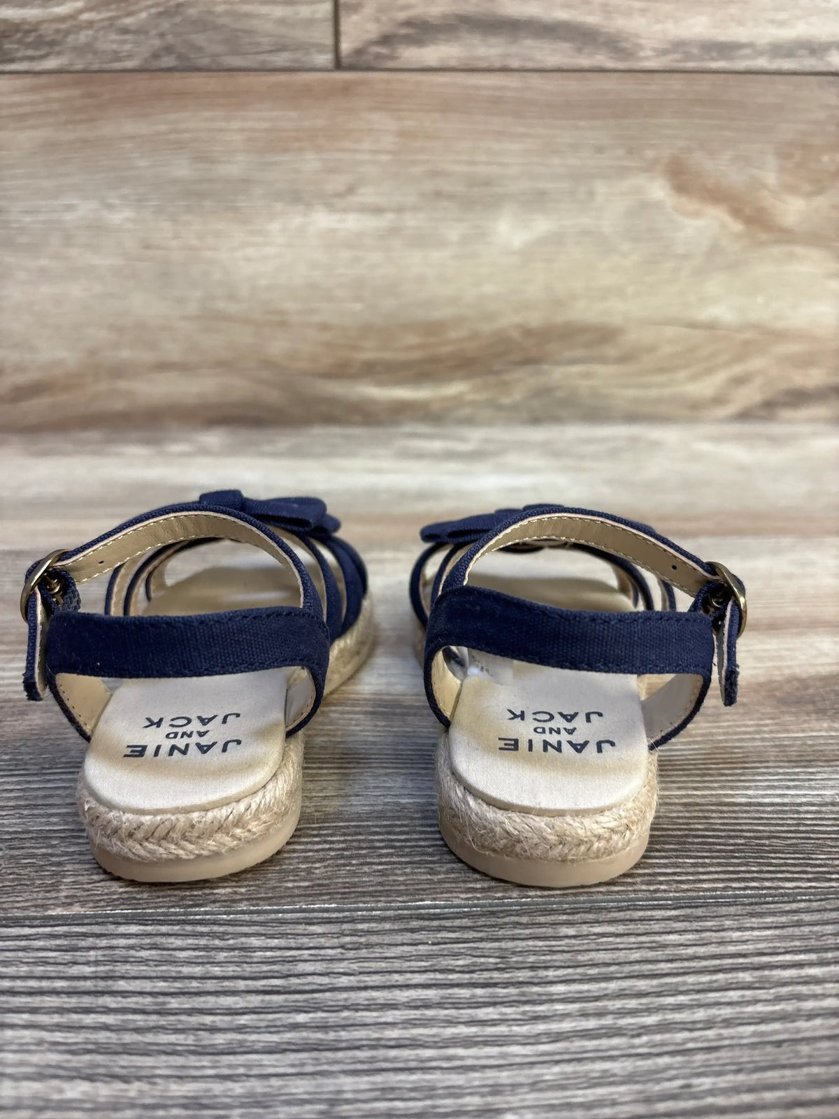 Pair of toddler navy blue sandals with ankle straps and rope soles on wood floor
