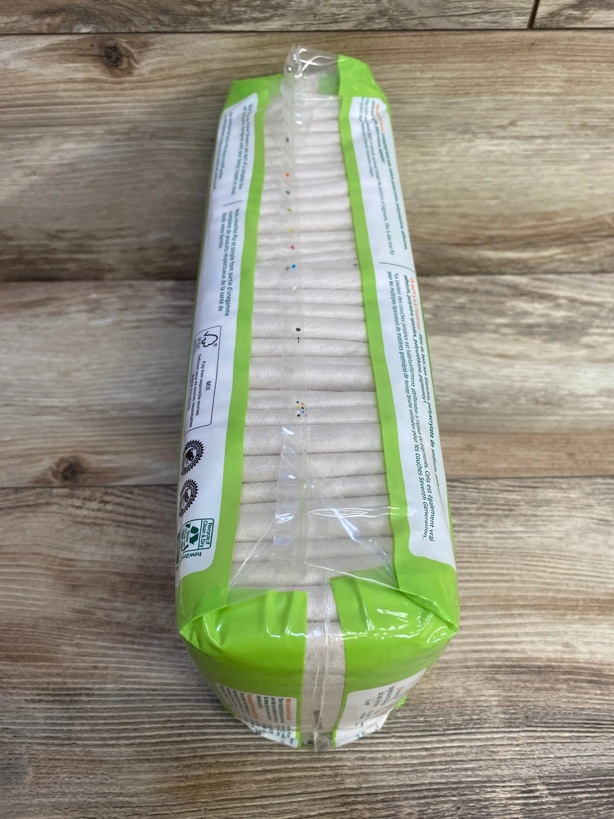 Top view of Seventh Generation Free & Clear size 1 diaper pack showing stacked diapers and green packaging on a wooden tabletop