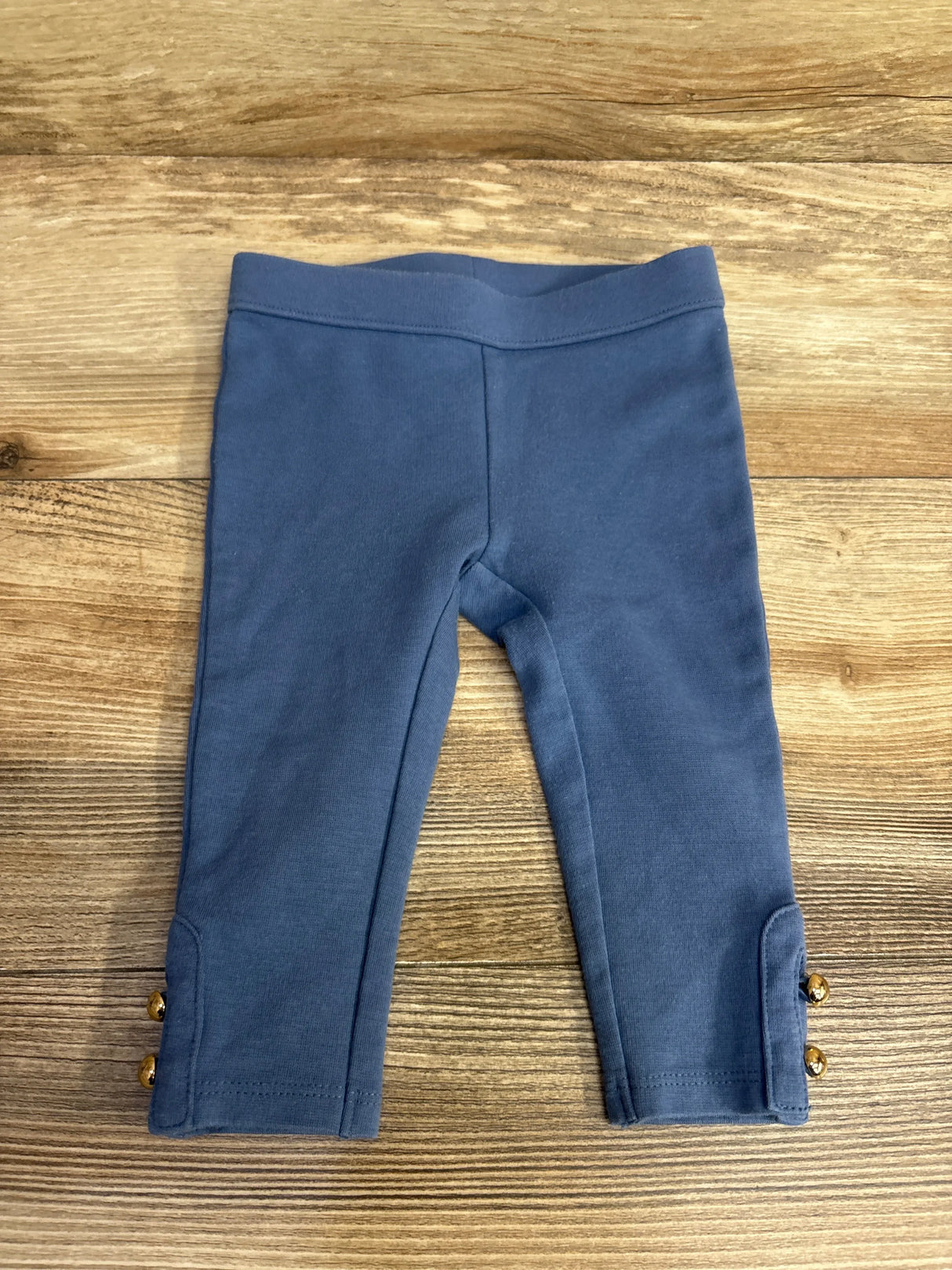 Blue toddler leggings with gold button details on wooden surface, kids clothes resale