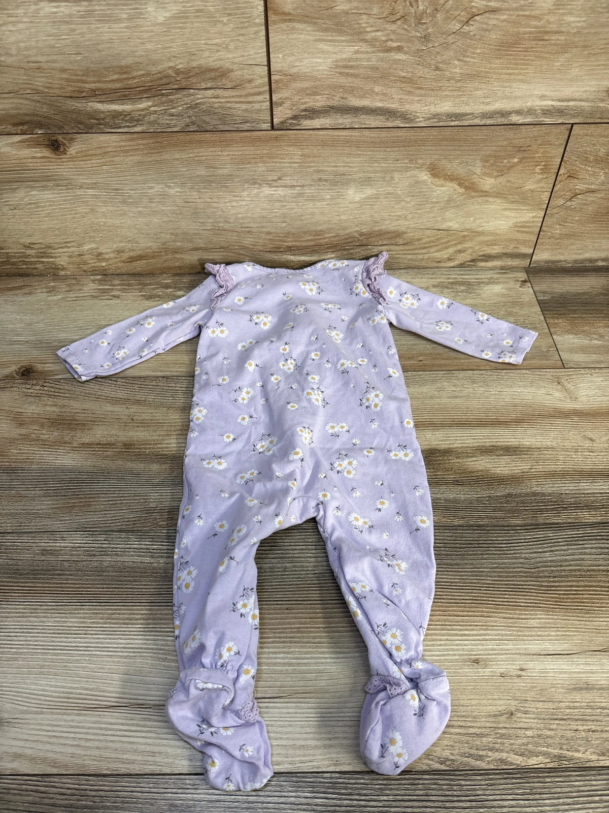 Top view of Jessica Simpson purple floral sleeper showcasing long sleeves and footed legs on a wood floor