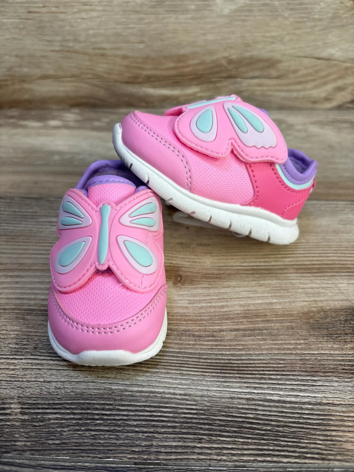 Three-quarter view of toddler pink butterfly sneakers showcasing mint-accented butterfly velcro strap and white sole on wood plank background