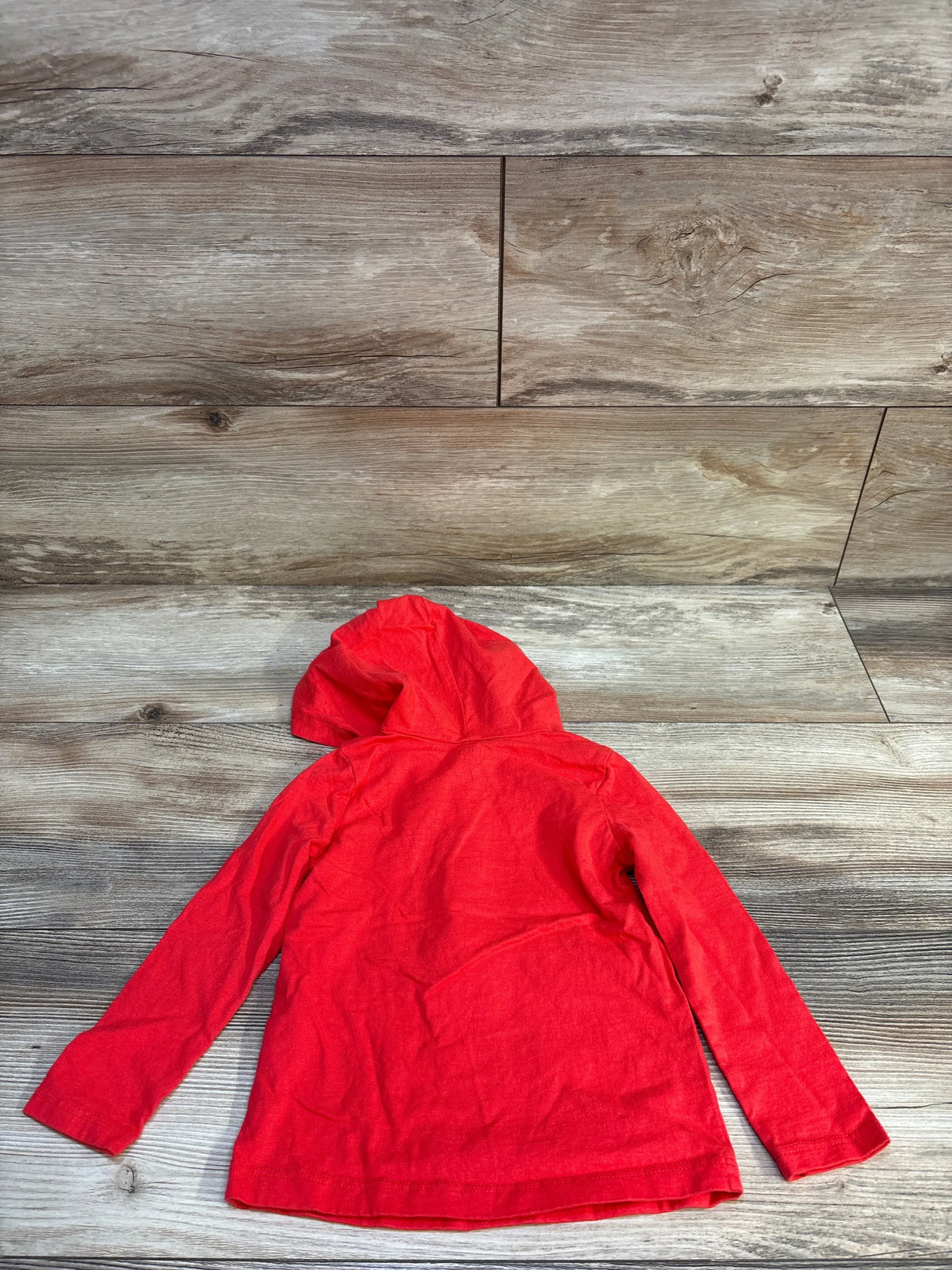 Red long sleeve kids hoodie laid flat on wood background