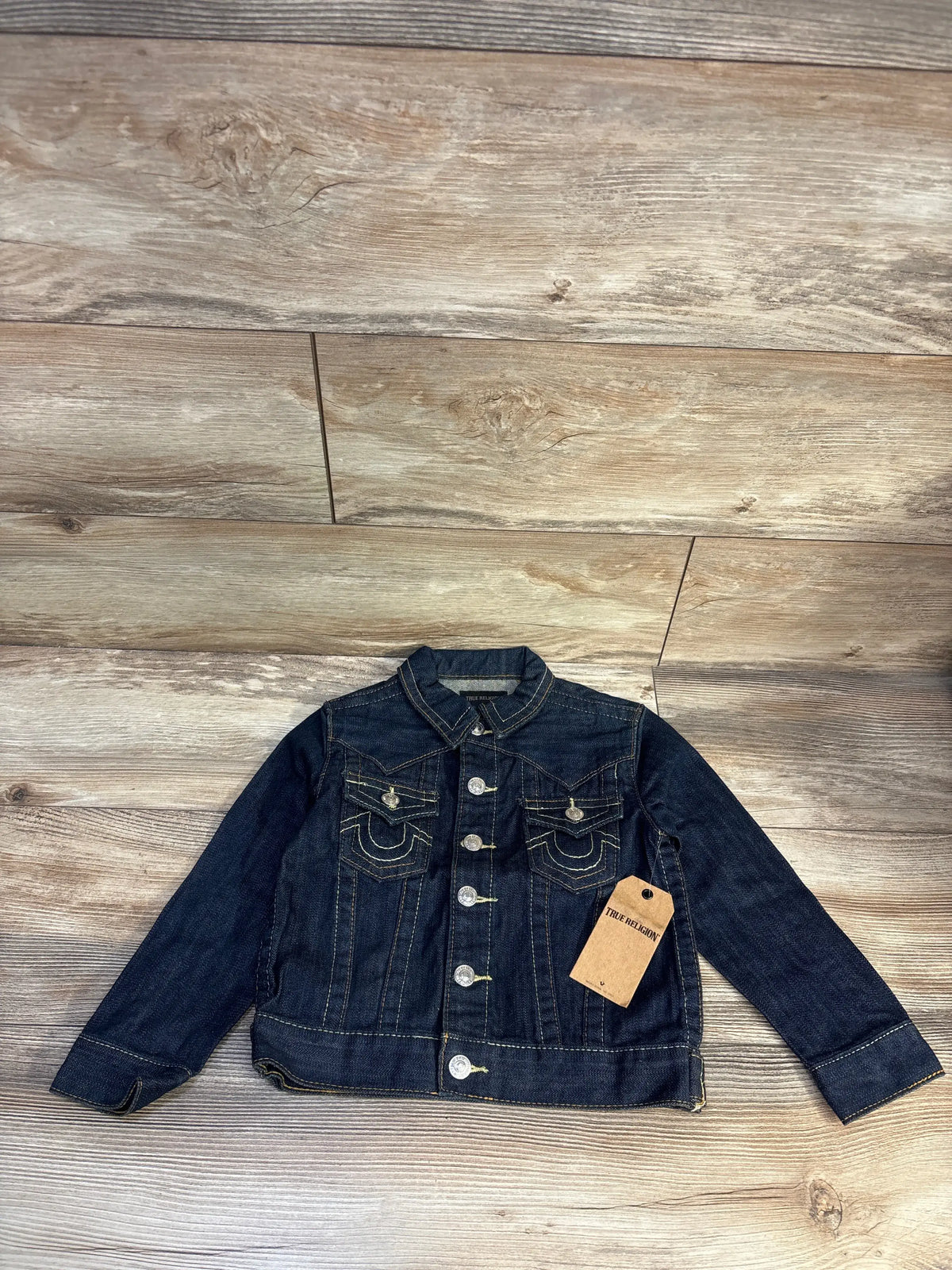 Front view of True Religion Jimmy Western Denim Jacket in blue with western yoke, horseshoe chest accents, on a wood floor