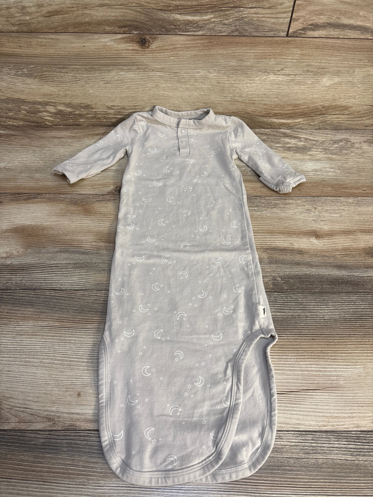 Light gray baby sleep gown with moon and star prints, long sleeves, laid on wood floor