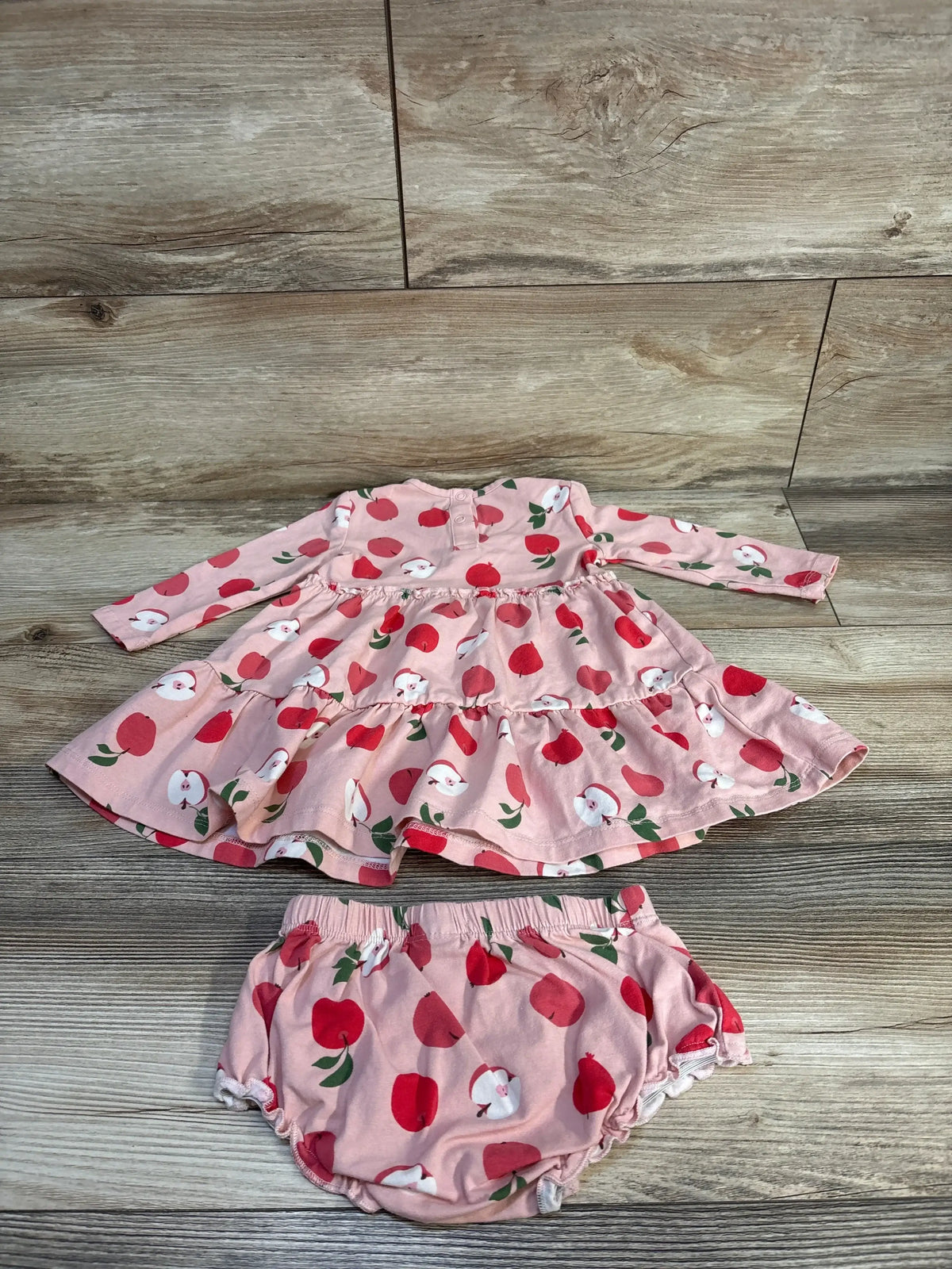 Pink toddler dress and bloomers set with red apple print on wooden background