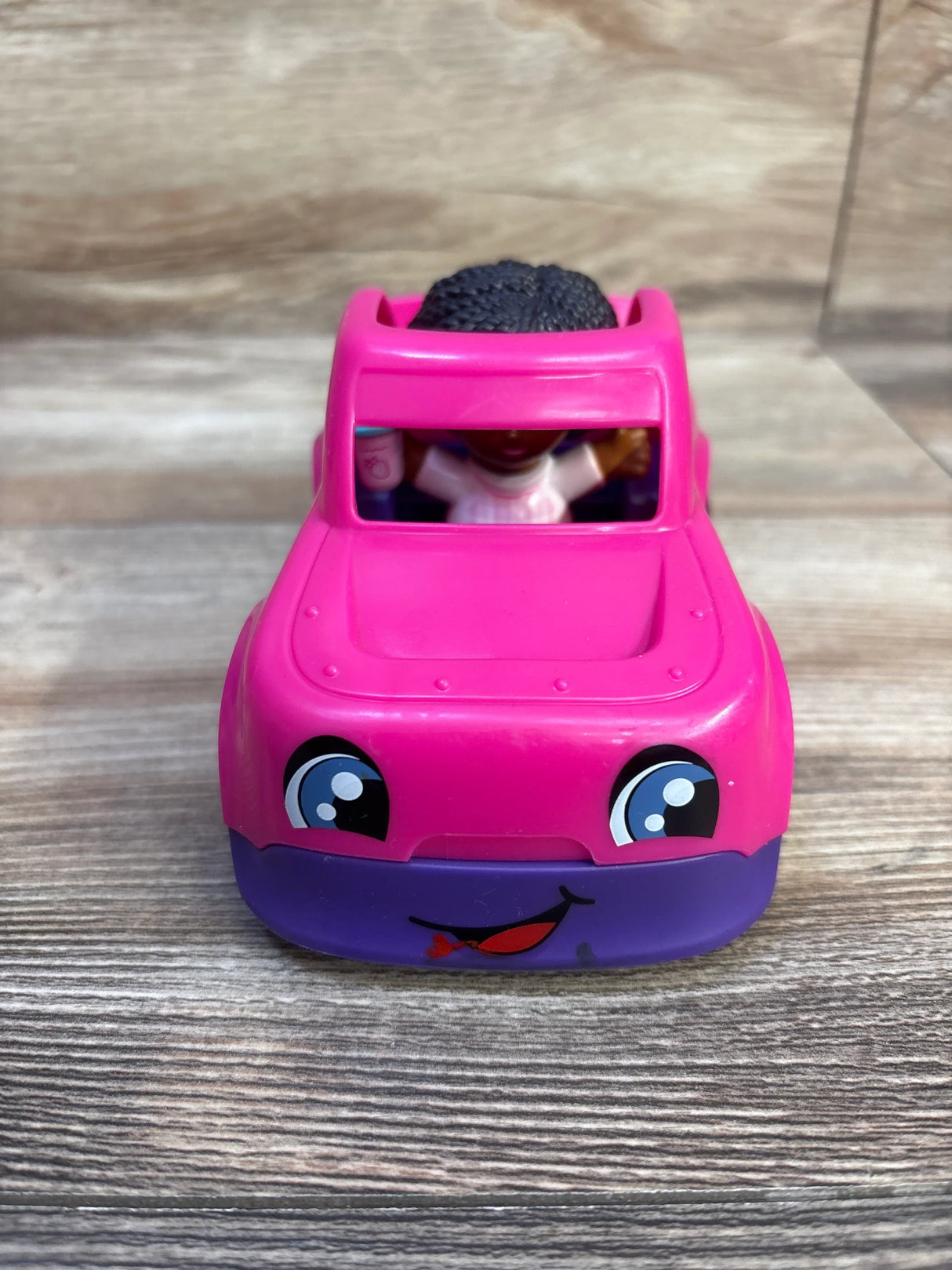 Front view of Fisher-Price Little People Barbie pink convertible showing smiling face decal and included little people figure on wood tabletop