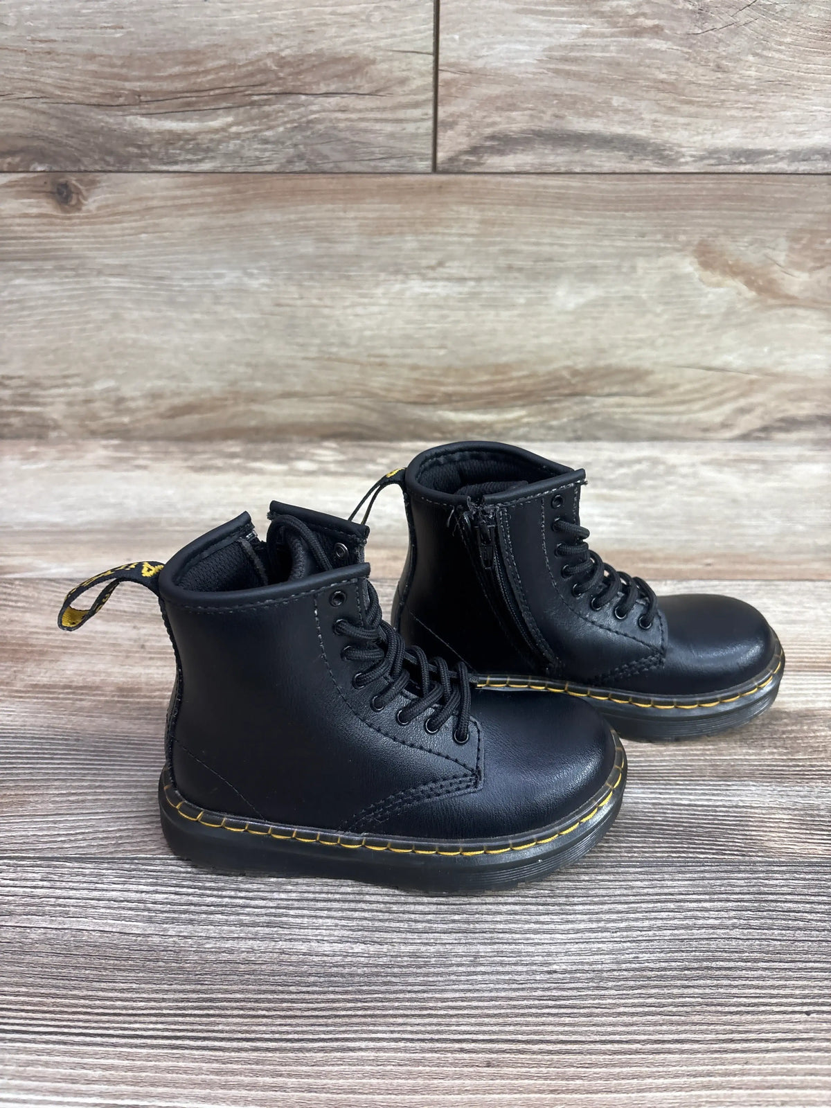 Pair of black Dr. Martens Softy boots for kids, size 9c, featuring side zippers and yellow stitching.