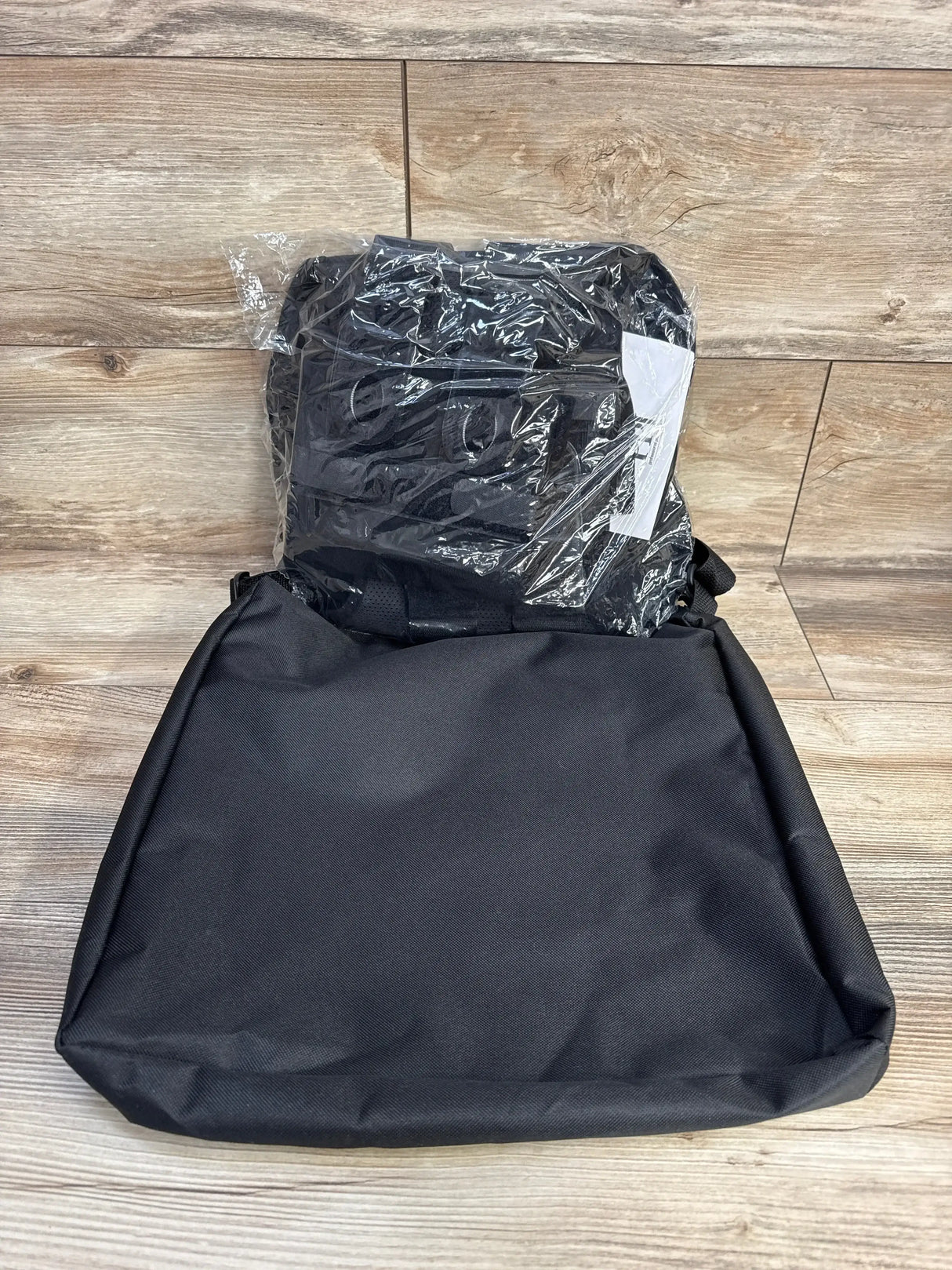 Flat-lay of folded black Matriarch maternity support belt in plastic showing straps and lumbar panel on wood background