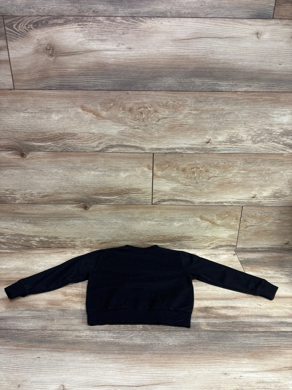 Flat view of the black I’m Just Here For The Snacks pullover sweatshirt with long sleeves on a wood-look floor