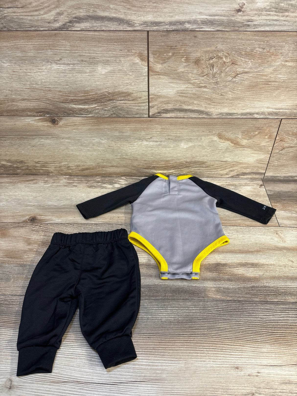 Flat lay of Nike Dri-Fit 2-piece bodysuit and joggers (3M) showing gray bodysuit with black sleeves and yellow trim and black pants