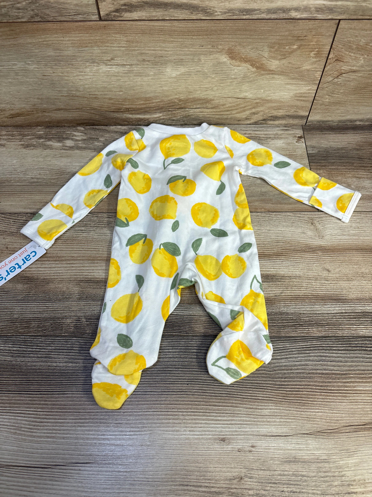White baby onesie with yellow lemon print, long sleeves, on wood floor