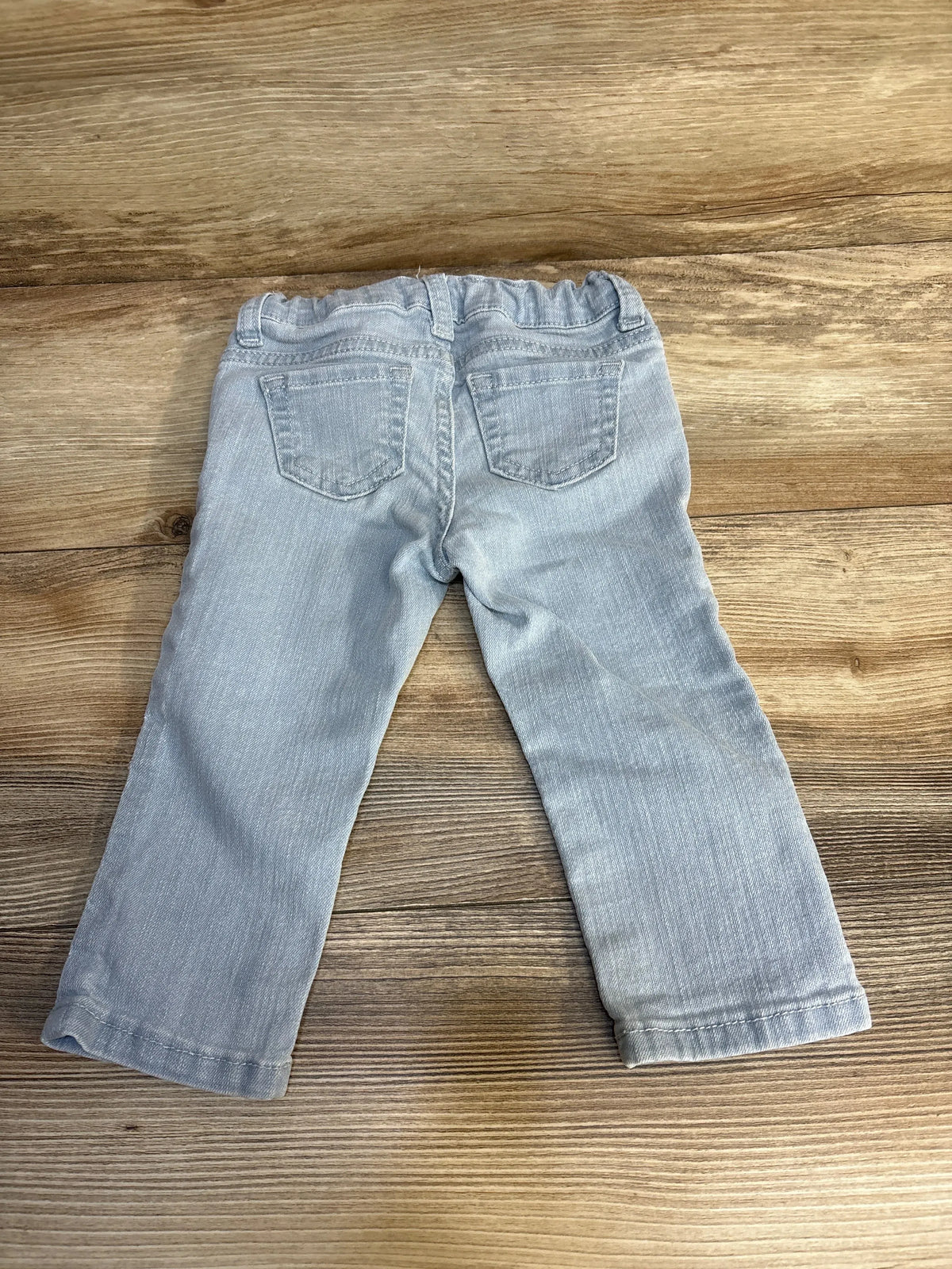 Light blue toddler jeans with elastic waist, laid flat on wood floor — kids clothing resale
