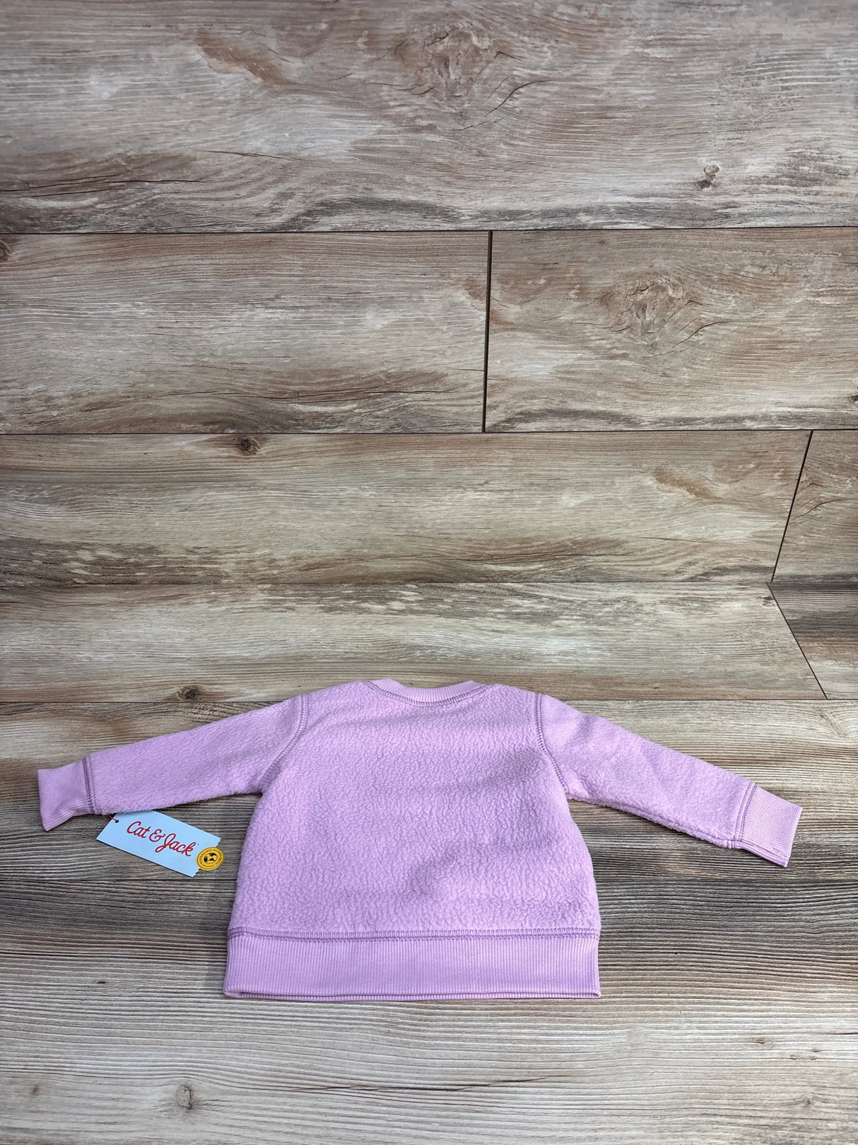 Light purple toddler fleece sweatshirt with Cat & Jack tag on wood background