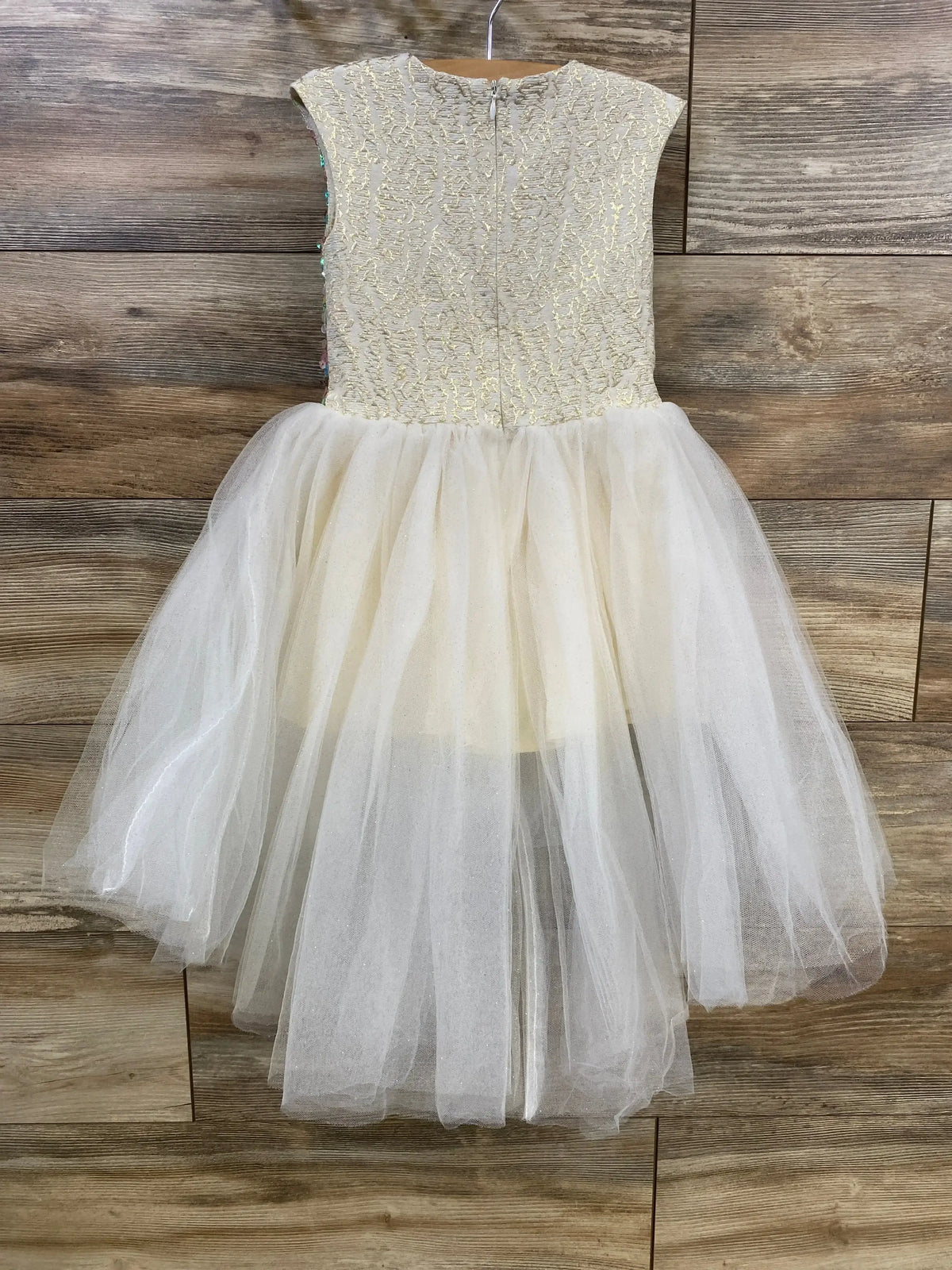 Back view of Halabaloo sequin tulle dress (2T) showing gold bodice, zipper, and full white tulle skirt on wood background