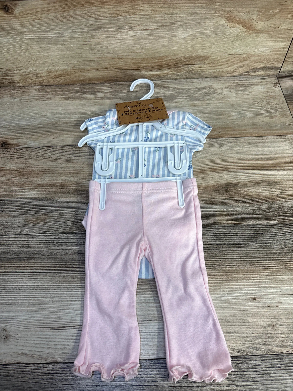 Front view of Dreamgro 2-piece bodysuit and pants set showing striped blue bodysuit and pink pants on a hanger