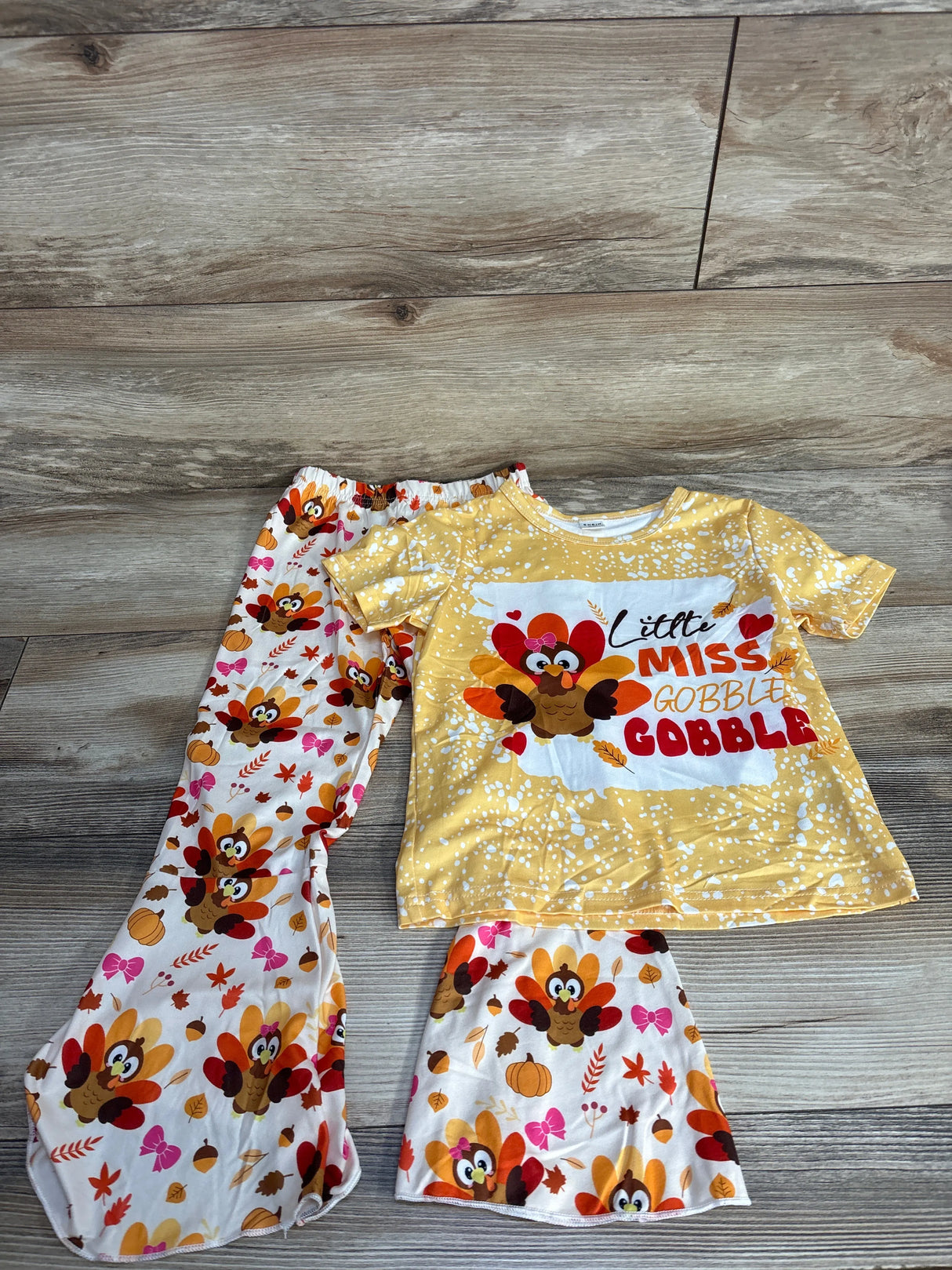 Kids Thanksgiving pajamas set with turkey print and 'Little Miss Gobble Gobble' top on wood floor
