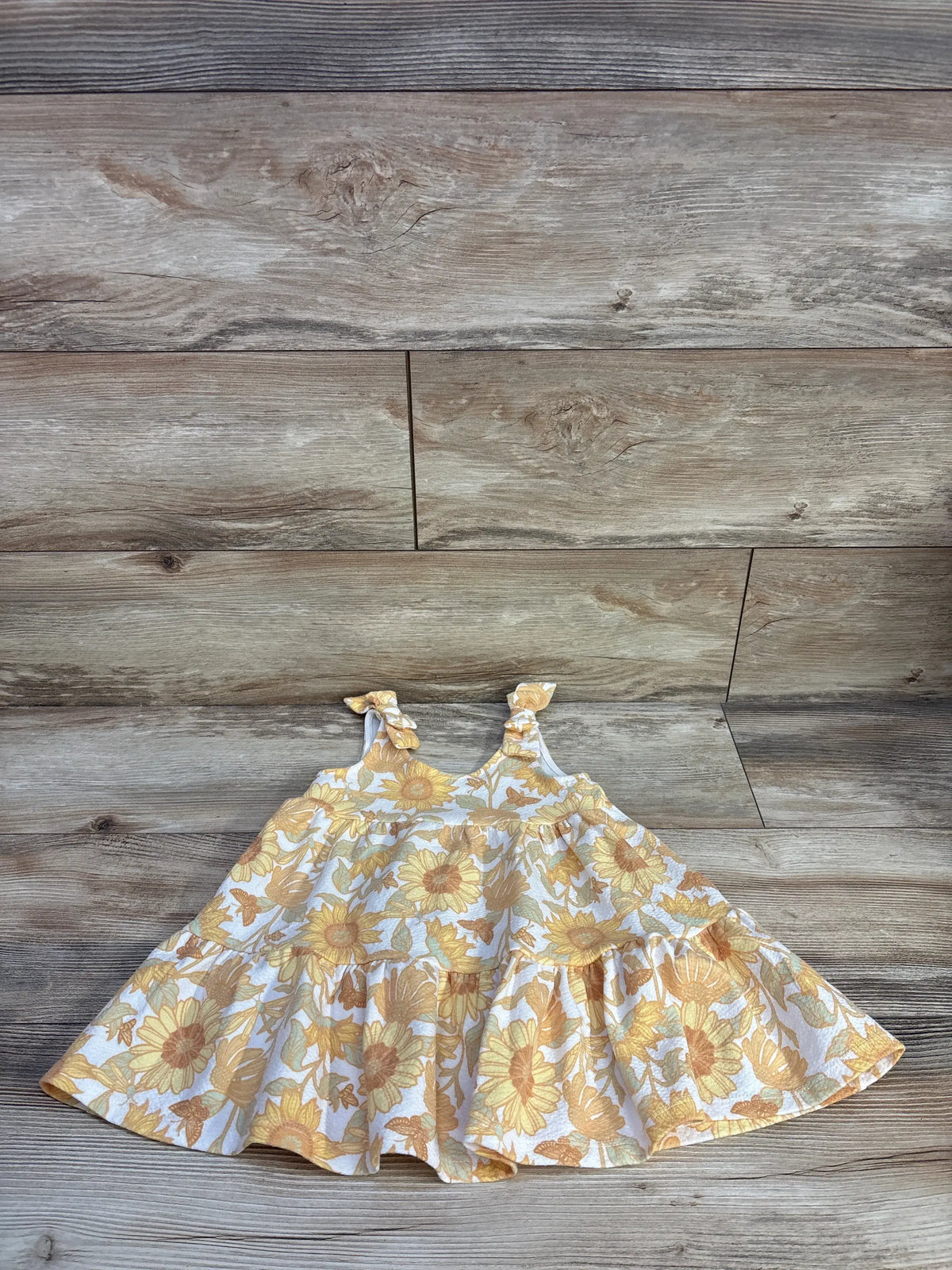 Front view of Sincerely Jules yellow floral tank dress showcasing its cheerful floral print and flared skirt on a wood-look background