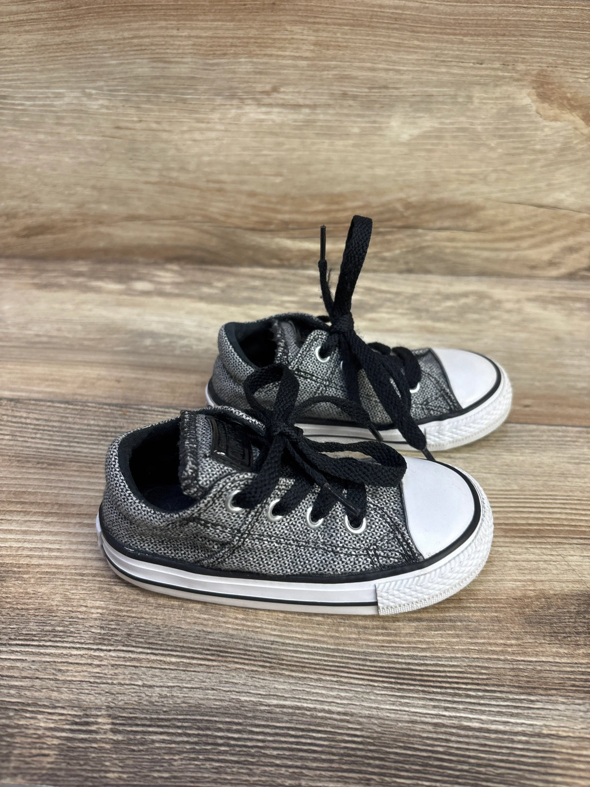 Three-quarter view of Converse Madison Ox low-top toddler sneakers, grey with black laces and white rubber toe cap, size 6C on wood floor